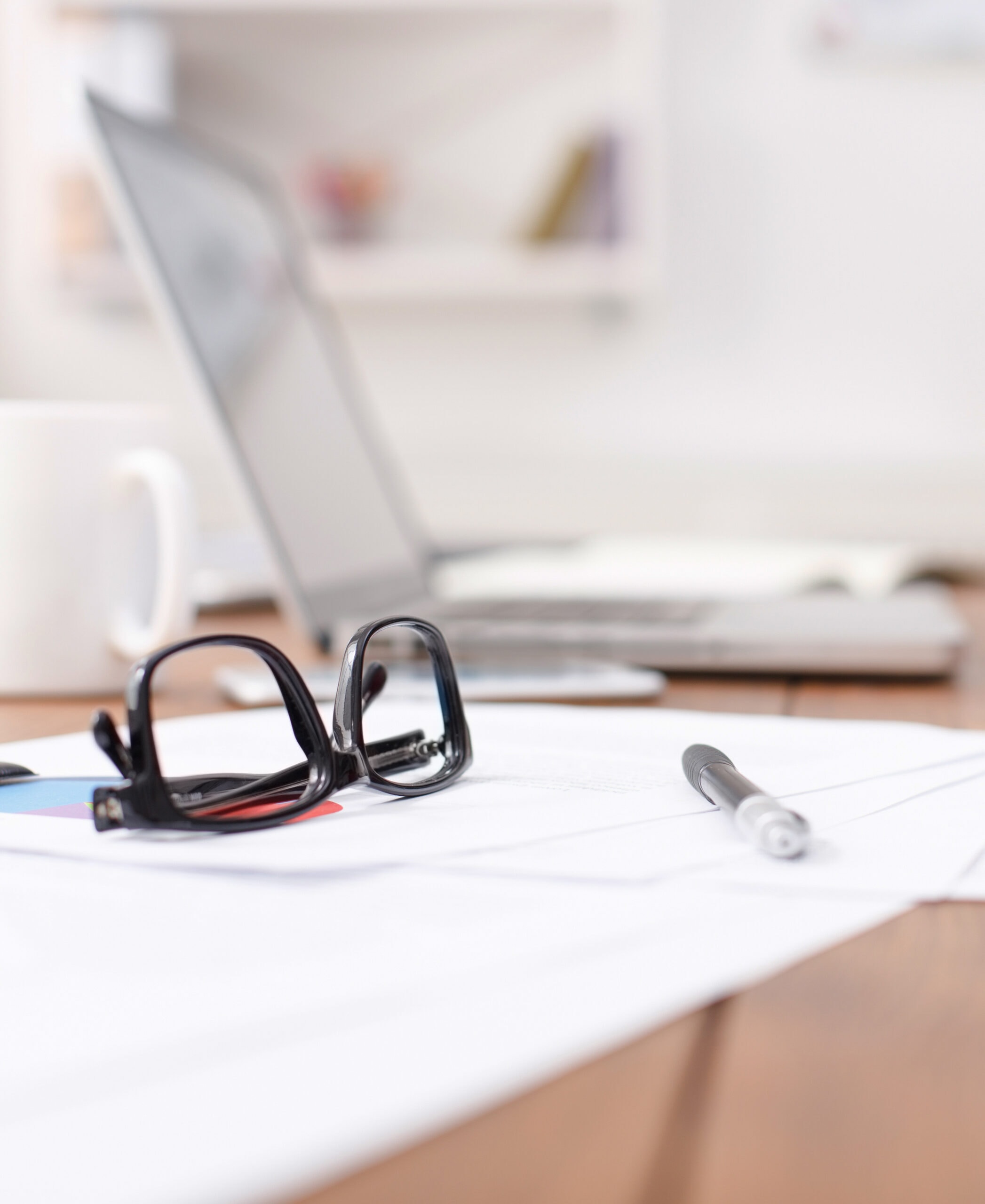 Side view of office desk with glasses, laptop and other items
